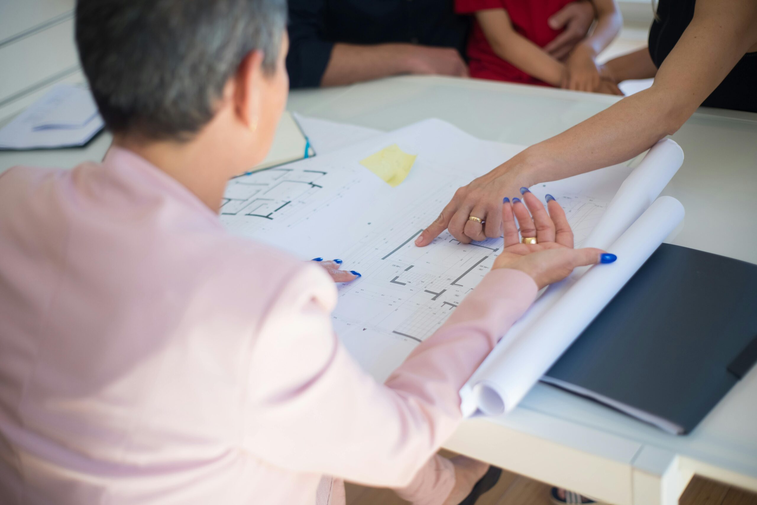 Group discussing architectural floor plans in an office setting.